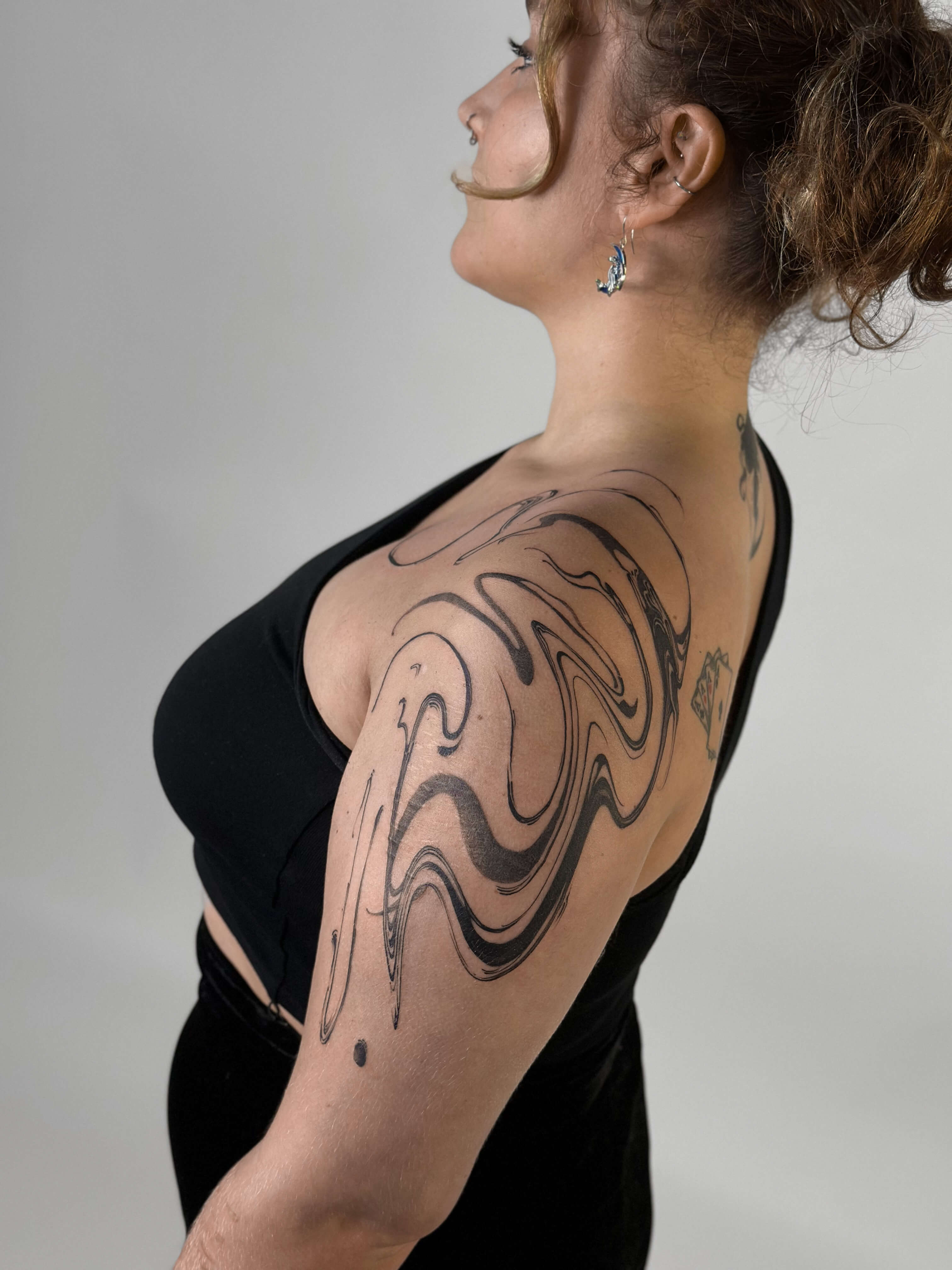 Abstract fluid graphic lines tattoo covering shoulder and upper arm — tattoo Barcelona